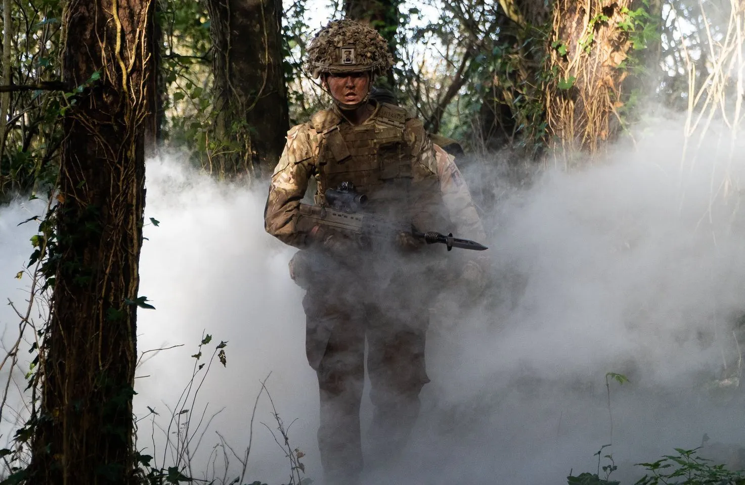 Female Rifleman walking through smoke filled woodland