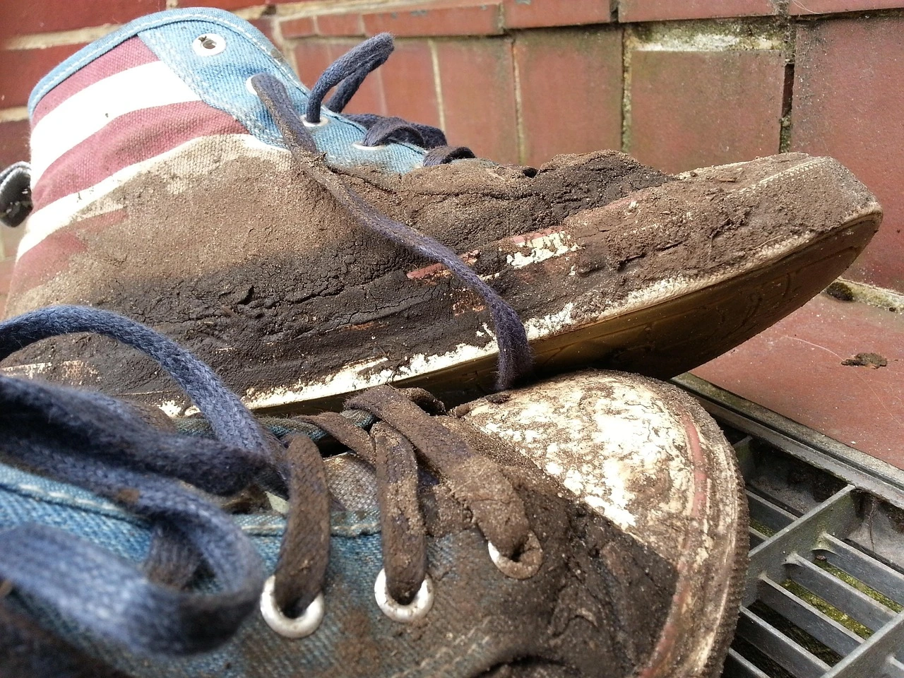 Das Bild zeigt ein paar Turnschuhe, an denen sehr viel Erde klebt.