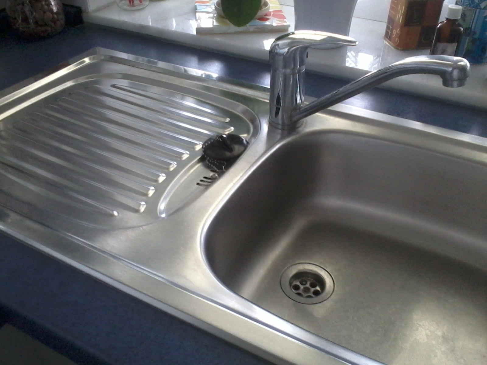 gereinigtes Spülbecken aus Edelstahl, umgeben von einer dunkelblauen Arbeitsfläche