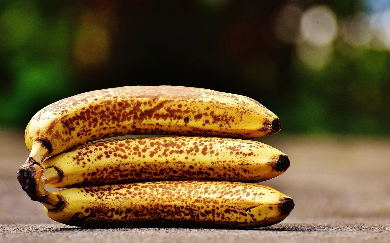 drei bereits bräunliche Bananen liegen auf einer grauen Fläche