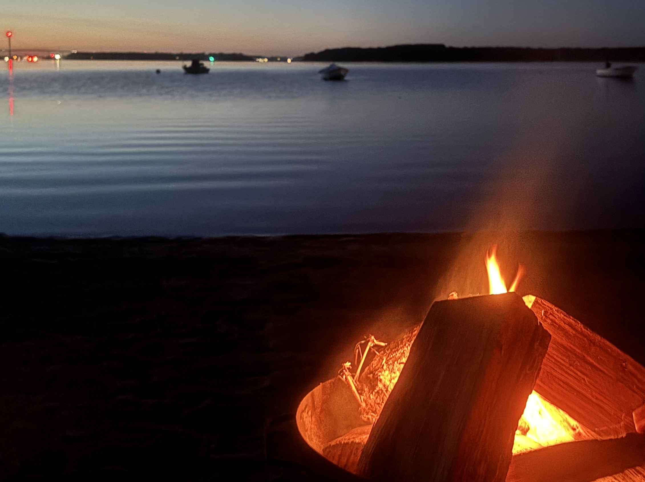 Zu sehen ist ein Lagerfeuer in einer Feuerschale vor der untergehenden Sonne mit Blick auf die Ostsee.